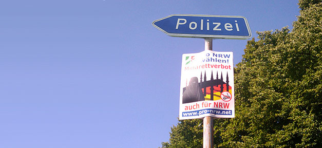 Die Polizei und ein Wahlplakat der rechtsextremen Pro NRW © Wam Kat © flickr.com (CC 2.0), bearb. MiG